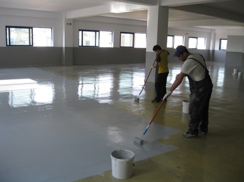 two man coating the floor with an epoxy for flooring in a commercial area of a building